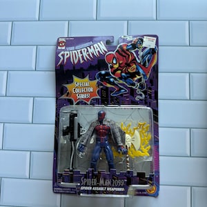 May include: A Spider-Man 2099 action figure in its original packaging. The figure is in a clear plastic case, with a red and blue costume, and a silver and yellow weapon. The packaging reads "The Amazing Spider-Man" and "Special Collector Series!"