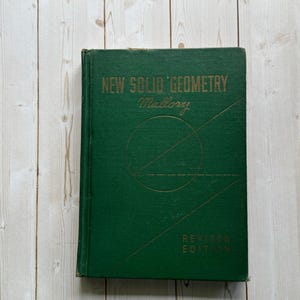 May include: A vintage hardcover book titled "New Solid Geometry" by Mallory. The book has a dark green cover with gold lettering and geometric designs. The words "Revised Edition" are also visible.