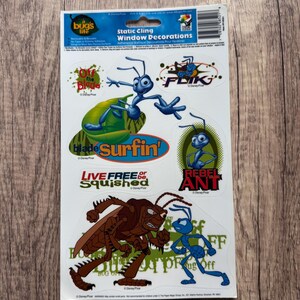 May include: A sheet of static cling window decorations featuring characters from the animated film "A Bug's Life." The stickers include images of ants, grasshoppers, and text such as "Flik" and "Rebel Ant."