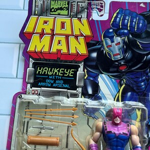 May include: Iron Man and Hawkeye action figure set. The packaging features the Marvel Comics logo and the words "Iron Man" in yellow and red. The Hawkeye figure is in a blue and purple costume, with a bow and arrow arsenal.