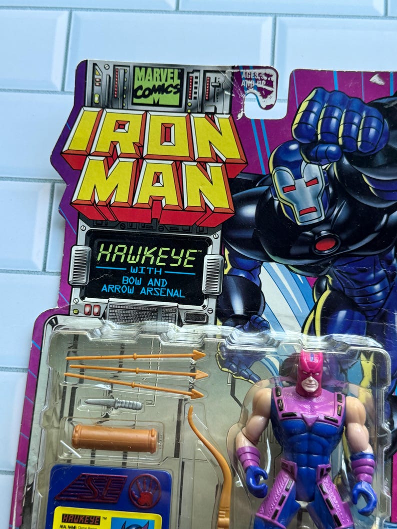 May include: Iron Man and Hawkeye action figure set. The packaging features the Marvel Comics logo and the words "Iron Man" in yellow and red. The Hawkeye figure is in a blue and purple costume, with a bow and arrow arsenal.