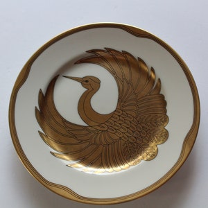 以下が含まれることがあります： 金色の縁取りとスタイリッシュな金の鶴のデザインが施された白いセラミックプレート
