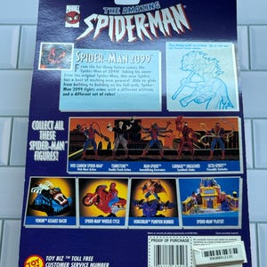 May include: The back of a Spider-Man action figure package. The package is primarily blue with the title "The Amazing Spider-Man" at the top. It features images of various Spider-Man characters and vehicles, including Spider-Man 2099.