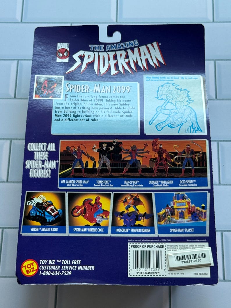 May include: The back of a Spider-Man action figure package. The package is primarily blue with the title "The Amazing Spider-Man" at the top. It features images of various Spider-Man characters and vehicles, including Spider-Man 2099.