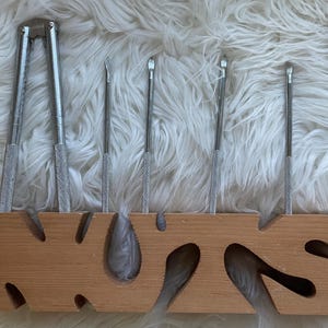 May include: A wooden stand with the word "NUTS" carved into it. The stand holds a nutcracker and five nut picks.