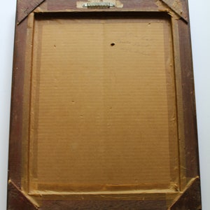 May include: A brown wooden frame with a cardboard backing. The back of the frame has handwritten text that reads "John List,  Built in 1937,  451 Oliver."