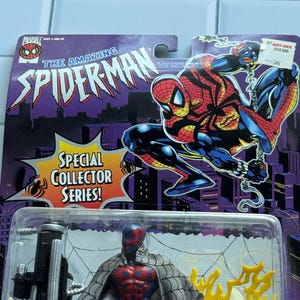 May include: A Spider-Man action figure from the Special Collector Series, packaged on a purple and black card. The figure is in a clear plastic case. The card features the words "The Amazing Spider-Man" and an illustration of Spider-Man.