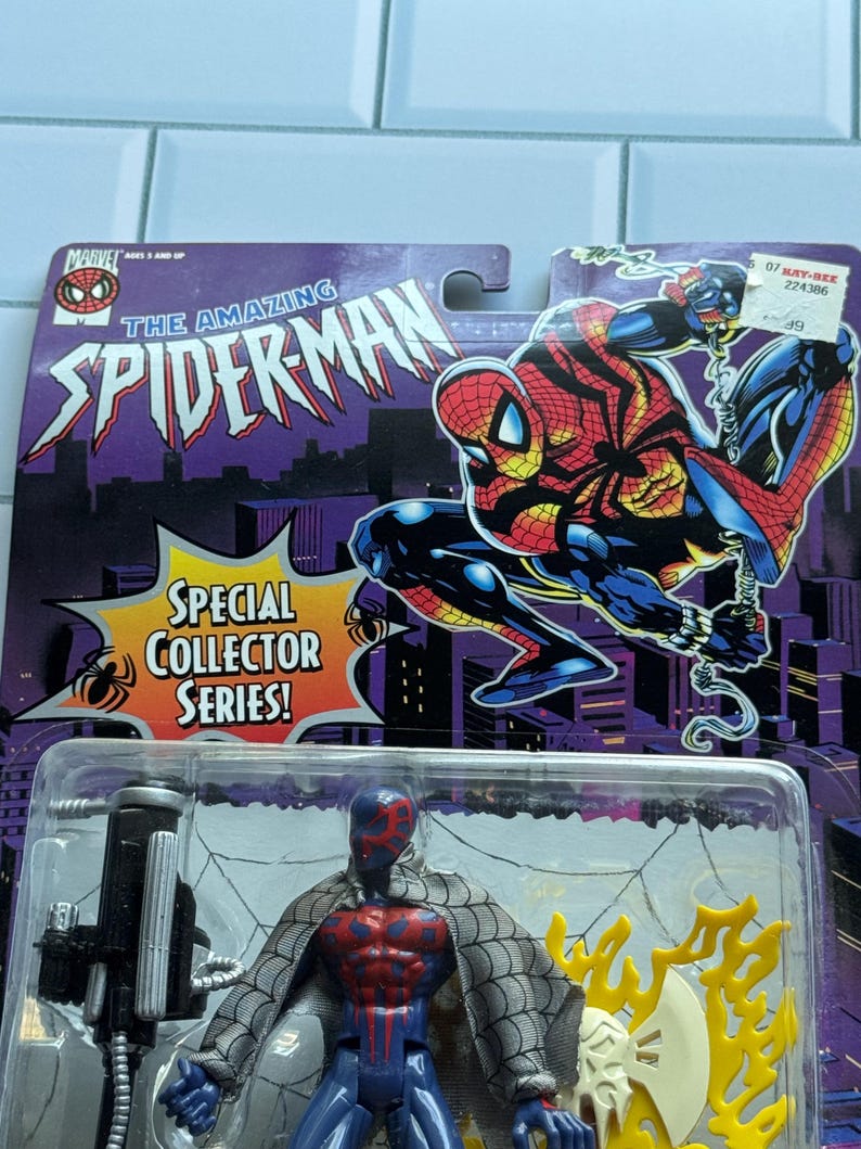 May include: A Spider-Man action figure from the Special Collector Series, packaged on a purple and black card. The figure is in a clear plastic case. The card features the words "The Amazing Spider-Man" and an illustration of Spider-Man.