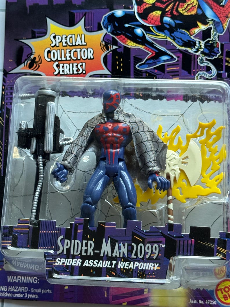 May include: Spider-Man 2099 action figure in a plastic package. The figure is blue with red accents and a gray webbed cape. It includes a black weapon and a yellow and white axe. The packaging reads "Special Collector Series!"