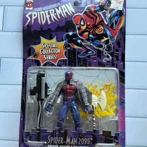 May include: A Spider-Man 2099 action figure in its original packaging. The packaging features the text "The Amazing Spider-Man" and "Special Collector Series!" The figure is blue, red, and gray, with a weapon. The packaging also includes a warning about choking hazards.