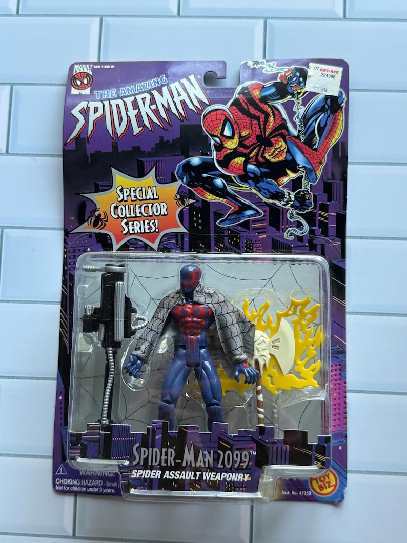 May include: A Spider-Man 2099 action figure in its original packaging. The packaging features the text "The Amazing Spider-Man" and "Special Collector Series!" The figure is blue, red, and gray, with a weapon. The packaging also includes a warning about choking hazards.