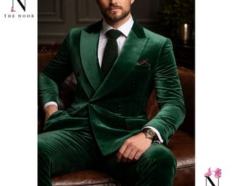 May include: A dark green velvet suit with a double-breasted jacket, white dress shirt, and black tie. The suit is worn with a gold watch. The text "THE NOOR" is in the upper left and lower right corners.