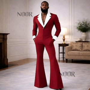 Op de afbeelding: Rode jumpsuit met witte kraag en manchetten. De jumpsuit heeft een uitlopend pijpenontwerp en een getailleerde pasvorm. Het woord "NOOR" staat in de linkerboven- en rechteronderhoek van de afbeelding.