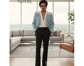 May include: A light blue blazer with a white shirt and black pants. The blazer has a wide lapel and a tailored fit. The pants are flared at the bottom. The image includes the text "NOOR".