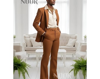 May include: A brown suit featuring a blazer and flared trousers. The suit is worn with a cream-coloured collared shirt and a gold chain. The image includes the text "NOOR" in the upper left and lower right corners.
