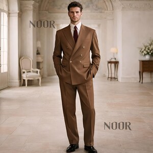 May include: A double-breasted brown suit with a white dress shirt and a burgundy tie. The suit has gold buttons and is worn with black dress shoes. The word "NOOR" is printed in the image.