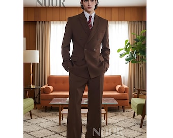 May include: A brown double-breasted suit with wide-leg trousers. The suit is worn with a white shirt and a red and black striped tie. The word "NOOR" is printed in the upper left corner and the lower right corner of the image.