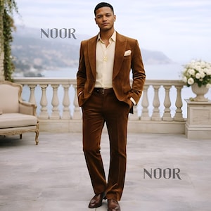 Puede incluir: Un traje de pana marrón, con blazer y pantalón a juego. Se lleva con una camisa color crema y zapatos de cuero marrón. Un colgante dorado y un pañuelo de bolsillo añaden detalles. La palabra "NOOR" está en la imagen.