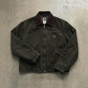 Op de afbeelding: Donkergroene werkjas met een bruine corduroy kraag. De jas heeft een volledige ritssluiting, meerdere zakken en een kleine logopatch op de borst. De jas is gemaakt van een duurzaam, versleten materiaal.