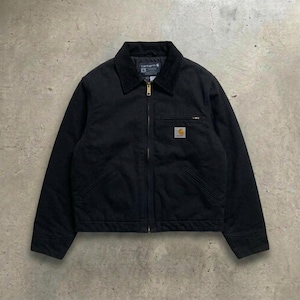 May include: A black Carhartt jacket featuring a corduroy collar, a full-length front zip, and a chest pocket with a zip closure. A rectangular Carhartt brand patch is stitched onto the left chest area, and the jacket has two lower pockets.