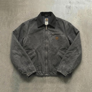 Puede incluir: Una chaqueta de trabajo gris carbón con cremallera, cuello oscuro y múltiples bolsillos. La chaqueta presenta un pequeño parche cuadrado con el logotipo en el pecho y una pequeña etiqueta cerca del cuello.