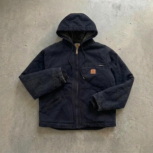 May include: A dark navy blue hooded jacket featuring a full-length front zip, long sleeves, and a drawstring hood. The garment includes a small rectangular tan brand patch on the left chest pocket and a dark interior lining visible at the hood.