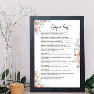 May include: A framed print titled "Litany of Trust" with floral decorations in peach and cream. The text is in a classic serif font. The print is displayed on a white surface.