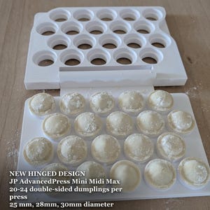 Op de afbeelding: Een witte kunststof scharnierende deegpers met een raster van ronde vormen. De tekst luidt: NEW HINGED DESIGN, JP AdvancedPress Mini Midi Max, 20-24 double-sided dumplings per press, 25 mm, 28 mm, 30 mm diameter. Rauw deeg ligt in de vormen.