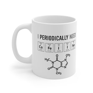 May include: White ceramic coffee mug with the text "I PERIODICALLY NEED" and a caffeine molecule diagram. The mug also features periodic table elements: Ca, Fe, I, and Ne. The mug has a curved handle.