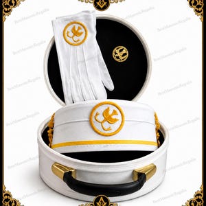 Puede incluir: Conjunto de regalia masónica blanca que incluye un sombrero, guantes y un pin, todos con un emblema dorado dentro de un círculo. El conjunto se presenta en un estuche blanco abierto con detalles dorados y un asa negra. El sombrero tiene una banda dorada.