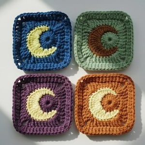 May include: Four square crochet coasters in shades of blue, green, purple, and orange. Each coaster features a crescent moon design in a contrasting color, with a yellow moon on the blue and purple coasters, and a cream moon on the green and orange coasters.