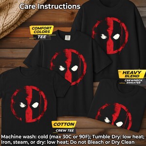 May include: Black t-shirts and a crewneck sweater featuring a red and white graphic design. The design resembles a mask with two white eye shapes and a red vertical stripe. The image includes care instructions: Machine wash cold, tumble dry low.
