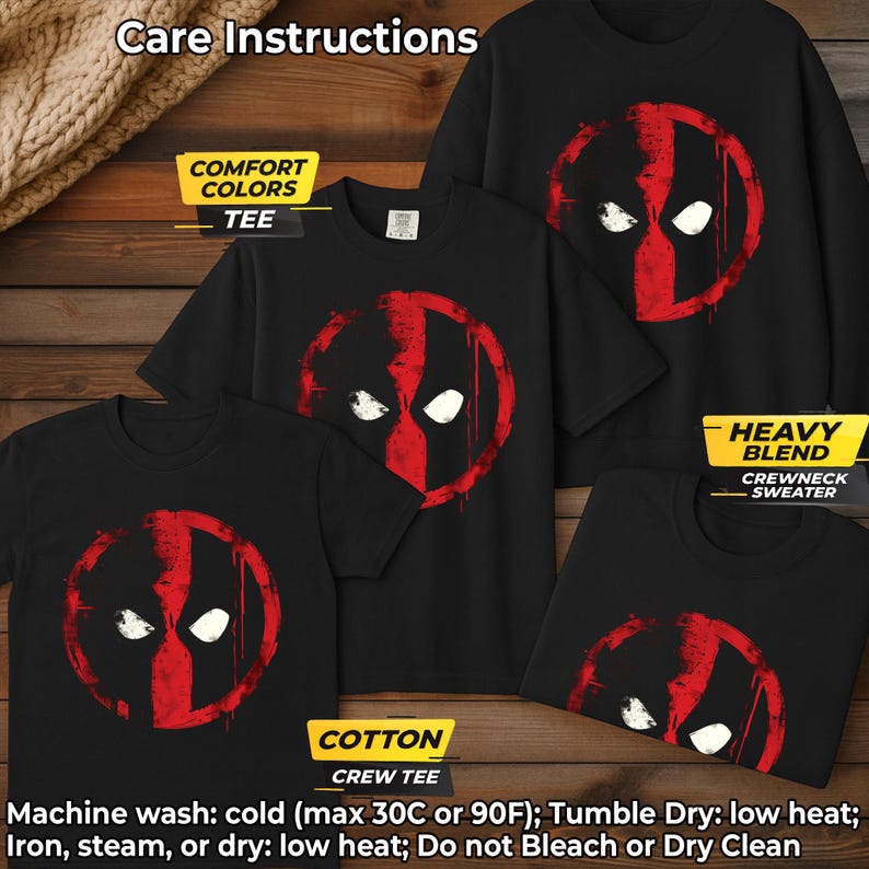 May include: Black t-shirts and a crewneck sweater featuring a red and white graphic design. The design resembles a mask with two white eye shapes and a red vertical stripe. The image includes care instructions: Machine wash cold, tumble dry low.