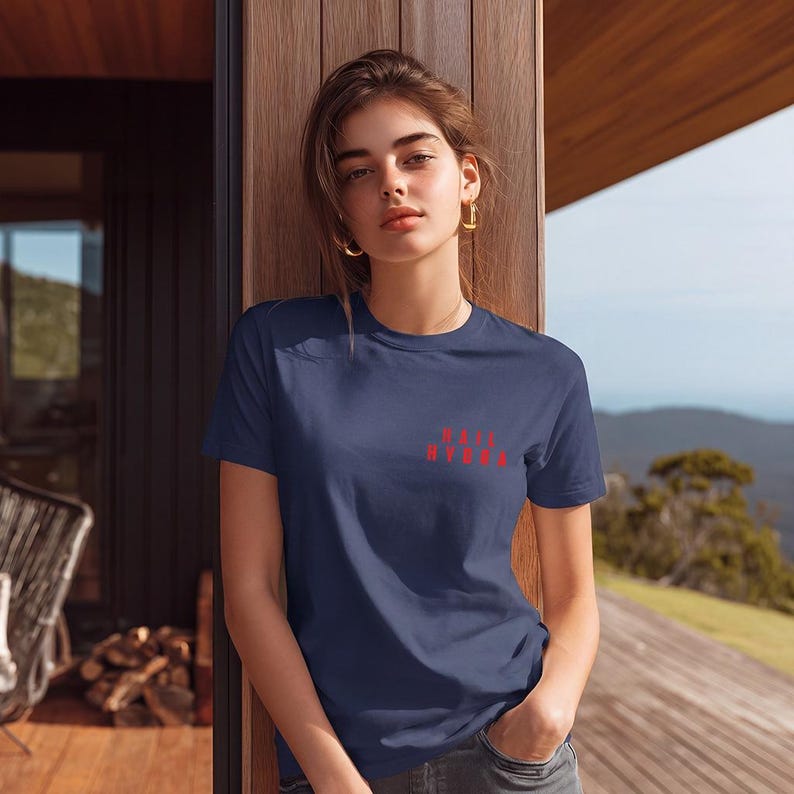 K&ouml;nnte beinhalten: Ein marineblaues Kurzarm-T-Shirt mit dem in Rot auf die linke Brust gedruckten Text "HAIL HYDRA". Das Kleidungsst&uuml;ck hat einen klassischen Rundhalsausschnitt und eine Standardpassform und besteht aus einfarbigem Stoff mit glatter Textur.