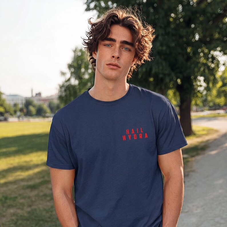 K&ouml;nnte beinhalten: Ein marineblaues Kurzarm-T-Shirt mit dem in Rot aufgedruckten Text "HAIL HYDRA" im oberen linken Brustbereich. Das Shirt verf&uuml;gt &uuml;ber einen Rundhalsausschnitt und eine Standardpassform aus einem einfarbigen Stoff mit matter Oberfl&auml;che.