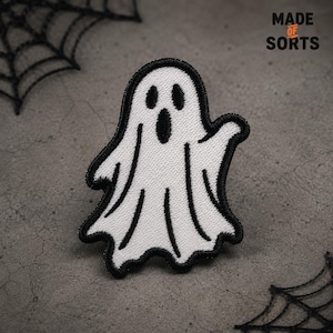 May include: A white ghost embroidered patch with a black stitched border, two oval eyes, and an open oval mouth. The ghost has a wavy bottom edge and one raised arm. The text MADE OF SORTS is printed in the upper right corner of the image.