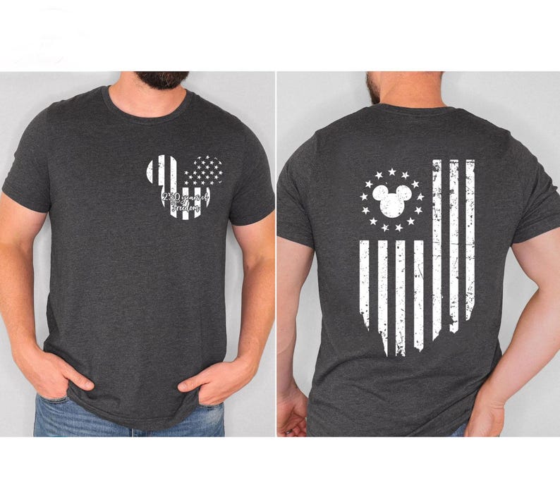 May include: Dark gray t-shirt featuring a Mickey Mouse-themed design. The front displays a Mickey head with stripes and stars, and the text "250 years of Freedom." The back showcases a distressed American flag design with a Mickey head and stars.