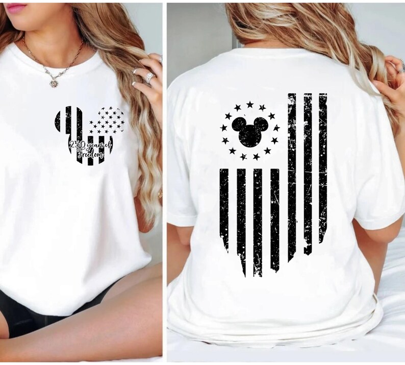 May include: White t-shirt featuring a black and white Mickey Mouse head design with the text "250 years of Freedom" on the front. The back of the shirt displays a distressed American flag design with a Mickey Mouse head and stars.
