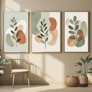 Peut inclure: Trois impressions d'art encadrées avec des motifs botaniques. Chaque impression présente des feuilles vert foncé et des formes abstraites en orange, vert et beige. Les cadres sont de couleur or clair. Thème moderne et minimaliste, idéal pour les intérieurs contemporains.