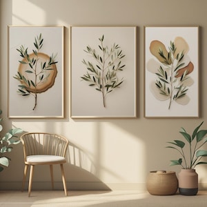 Peut inclure: Trois impressions d'art encadrées représentant des branches d'olivier. Les impressions ont une palette de couleurs neutres avec des fonds beiges et des cadres dorés. L'une comprend une tranche de bois, l'autre des formes abstraites.