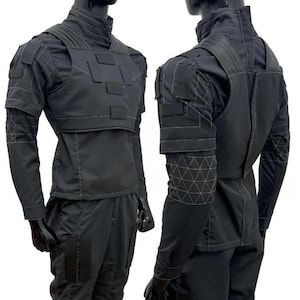 May include: Black tactical outfit displayed on a mannequin. The outfit includes a high-collared shirt, a vest with rectangular panels, and matching pants. The sleeves and shoulders feature geometric stitching. The overall design is sleek and modern, suitable for cosplay or tactical applications.