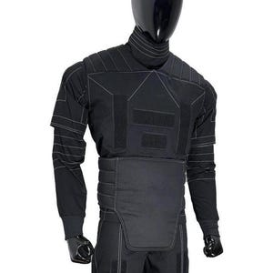 Puede incluir: Un conjunto t&aacute;ctico negro de camisa de manga larga y pantal&oacute;n con cuello alto, paneles acolchados en los hombros y una secci&oacute;n abdominal reforzada. La prenda incluye costuras blancas en contraste y m&uacute;ltiples parches rectangulares de velcro.