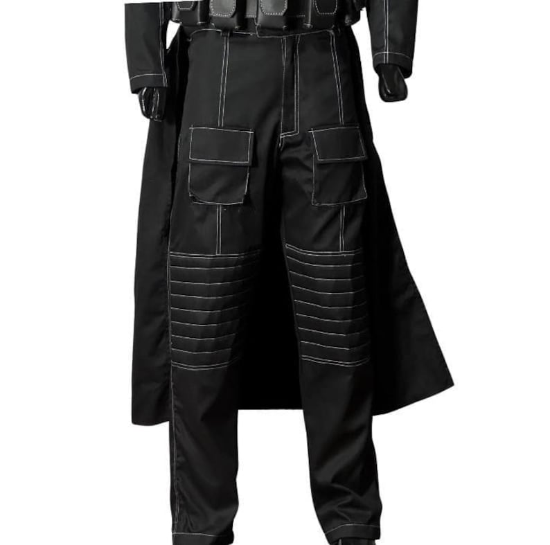 May include: Black tactical trousers with white stitching. The trousers have multiple pockets and reinforced knee panels. A black coat is visible in the background. The trousers are part of a costume or uniform.