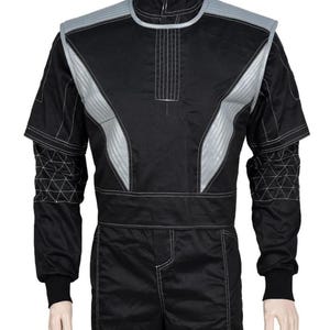 May include: Black racing suit with silver accents on the shoulders and chest. The suit has a high collar and white stitching details. The sleeves have geometric patterns near the cuffs. The suit is designed for motorsports.