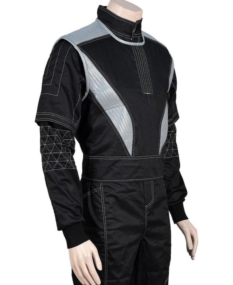 May include: Black racing suit with silver accents on the shoulders and chest. The suit features white stitching and a high collar. The sleeves have a geometric pattern near the elbow. The suit has a fitted waist and is designed for motorsports.