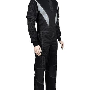 May include: Black racing suit with silver accents and white stitching. The suit features a high collar, a zip-up front, and reinforced panels on the knees. The sleeves have a unique geometric design. The suit is displayed on a mannequin.
