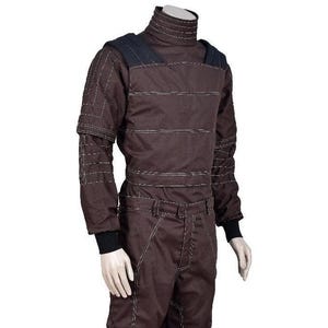 May include: A dark brown long-sleeved jumpsuit featuring a high mock neck collar, black shoulder panels, and black ribbed cuffs. The garment is detailed with prominent white topstitching throughout the bodice, sleeves, and trousers.