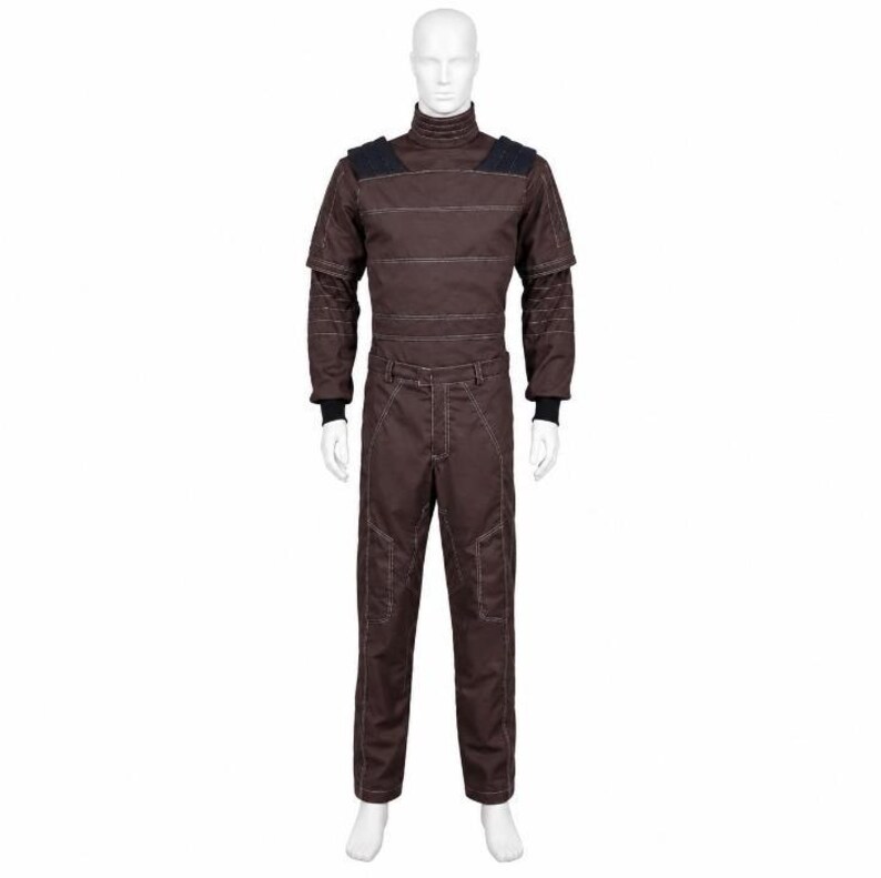 May include: A dark brown long-sleeved jumpsuit featuring a high mock neck collar, black shoulder panels, and visible white topstitching throughout the garment. The jumpsuit includes fitted black cuffs at the wrists and a structured, utilitarian design.