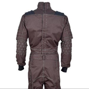 May include: A dark brown jumpsuit featuring a high collar with a zipper closure, long sleeves with quilted triangular patterns on the forearms, black ribbed cuffs, and prominent white contrast stitching throughout the garment's seams and panels.