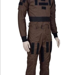 May include: Brown jumpsuit with black accents. The outfit features a high collar, long sleeves, and multiple black rectangular patches on the chest, arms, and legs. A black band defines the waist. The jumpsuit is designed for a costume or cosplay.